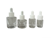 Four sizes of premium clear glass dropper bottles (5ml, 10ml, 20ml, 30ml) featuring a distinct round heavy thick-base design for luxury skincare products.